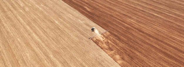 Un trattore nel campo coltiva il terreno prima dell'inizio della campagna di semina Vista dal drone