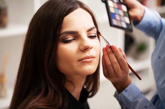 Un truccatore professionista realizza un trucco da sera per una giovane donna.