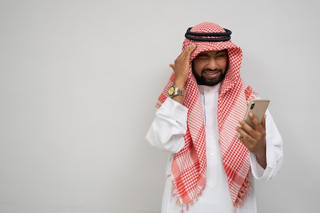 Un turbante arabo ha le vertigini mentre usa un telefono cellulare con le mani che gli tengono la testa