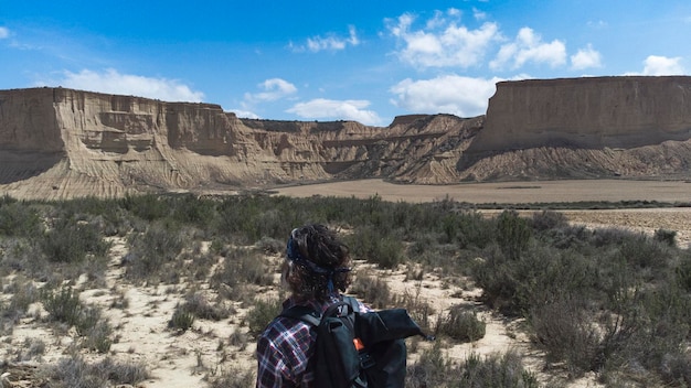 Un turista di mezza età che porta uno zaino si affaccia sul paesaggio desertico nel parco naturale di Bardenas Reales Navarra
