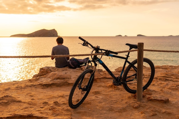 Un turista in bicicletta sulla spiaggia di Cala Comte sull'isola di Ibiza Tramonto Baleari