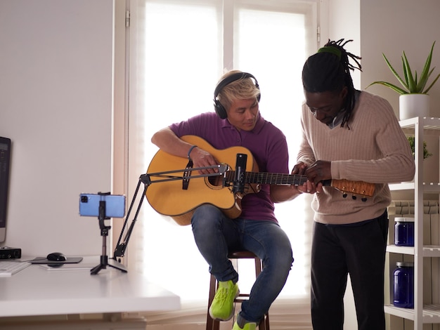 Un tutor personale afroamericano spiega al suo studente asiatico come suonare correttamente l'accordo studiato Educazione musicale a casa