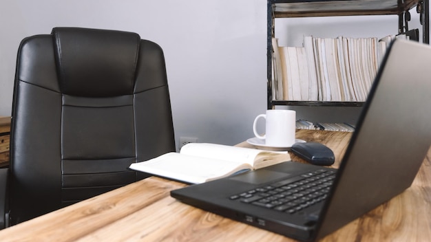 un ufficio con una sedia una scrivania un portatile un telefono un quaderno e una tazza di caffè sfondo del concetto