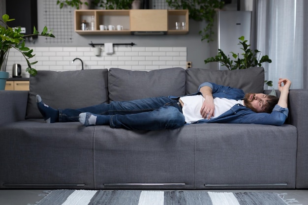 Un uomo a casa stanco dopo il lavoro dorme sul divano