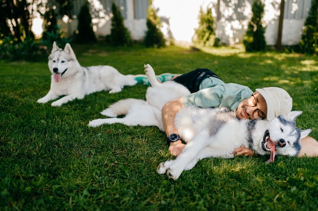 Un uomo adorabile e due cani in posa sull'erba