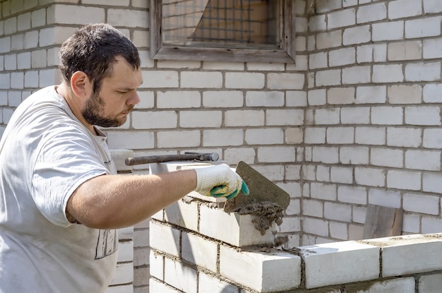 Un uomo adulto con la barba posa i mattoni