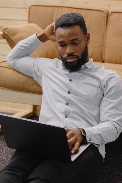 Un uomo afroamericano bello e giovane in un ufficio o in un coworking lavora su un laptop