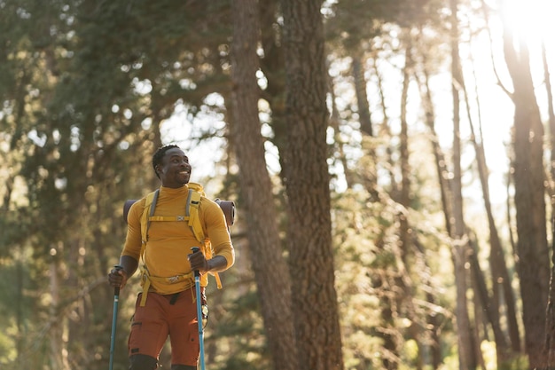 Un uomo afroamericano felice nella foresta al tramonto un escursionista con uno zaino che celebra il successo all'aperto persone successo e concetto sportivo