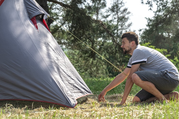 Un uomo all'aperto in procinto di montare una tenda.