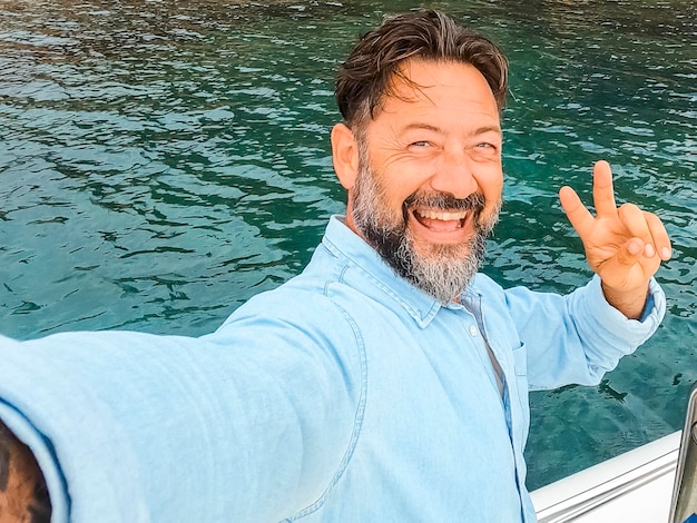 Un uomo allegro e felice con un'espressione emozionata sul viso che si fa un selfie in piedi all'interno di una barca durante un tour di escursione in mare in vacanza estiva vacanza di viaggio persone maschili che si godono la vita e il turismo