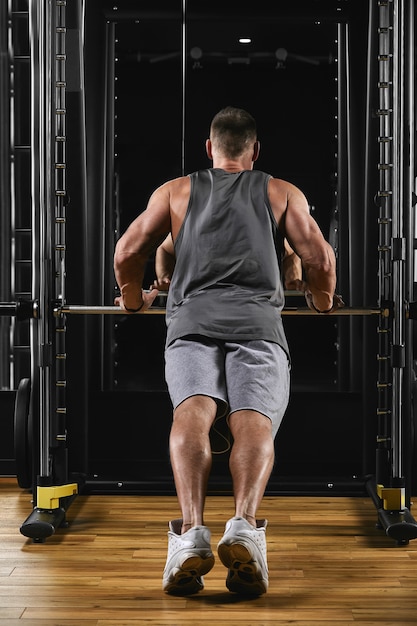 Un uomo allena le braccia e il petto in palestra sul simulatore, fa esercizi