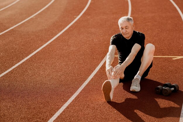 Un uomo anziano che si allunga su una pista