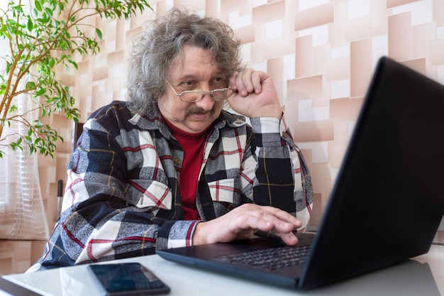 Un uomo anziano con problemi di vista che lavora al computer