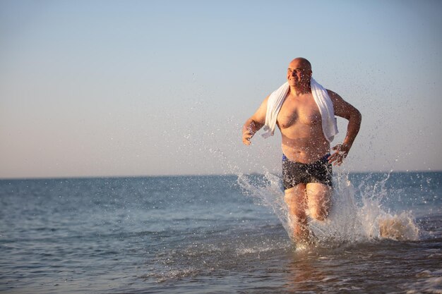 Un uomo anziano corre lungo la spiaggia