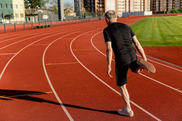 Un uomo anziano corre su una pista e indossa una camicia nera.