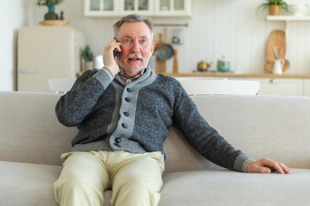 Un uomo anziano felice di mezza età che parla allo smartphone con gli amici della famiglia, un nonno più anziano e maturo con