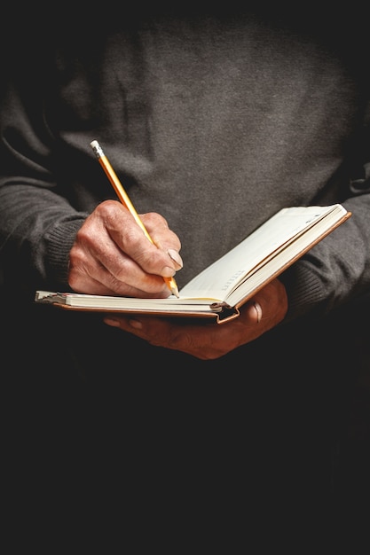 Un uomo anziano ha scritto a matita su un taccuino