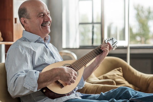 Un uomo anziano impara a suonare la chitarra