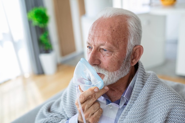 Un uomo anziano malato che fa la medicina per l'inalazione è la migliore medicina. Un uomo maggiore malato che indossa una maschera di ossigeno e che si sta curando per la covid-19 Un uomo maggiore con un inalatore.