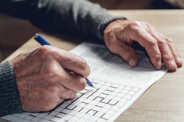 Un uomo anziano risolve un sudoku o un cruciverba