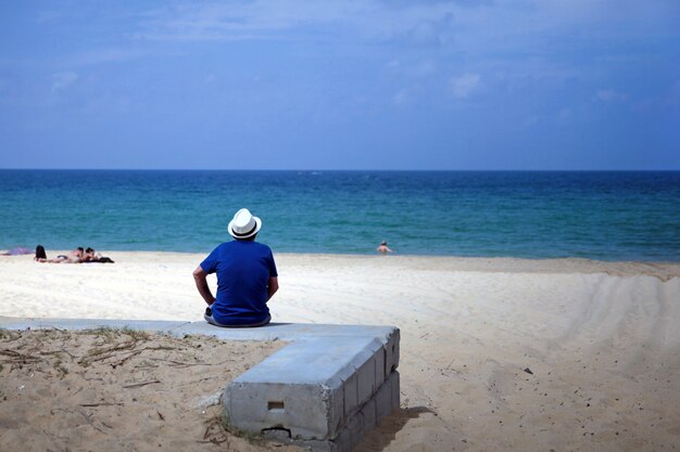 Un uomo anziano si rilassa seduto sulla spiaggia in una giornata limpida