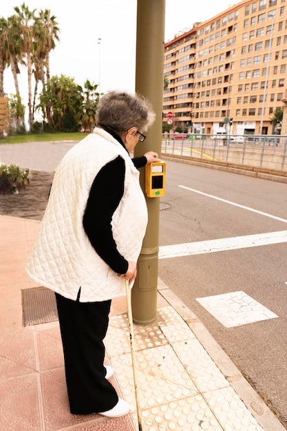 Un uomo anziano usa un pulsante di attraversamento pedonale in una strada della città Tecnologie di sicurezza della città intelligente