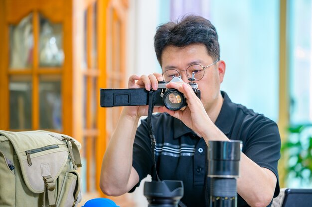 Un uomo asiatico di mezza età il cui hobby è la fotocamera SLR con pellicola da 35 mm / 135 mm