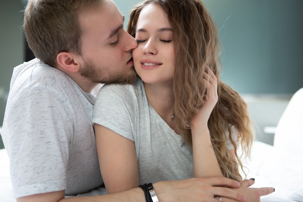 Un uomo bacia dolcemente una bella ragazza che ha chiuso gli occhi con piacere