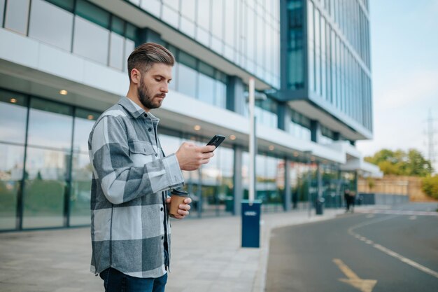 Un uomo barbuto che naviga con sicurezza nel cyberspazio sul suo dispositivo mobile in un ambiente urbano barbuto