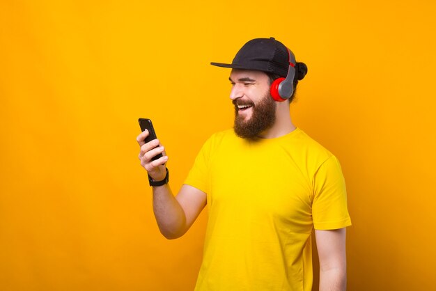 Un uomo barbuto felice sta parlando al suo telefono e sta ascoltando la musica allo stesso tempo