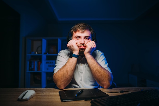 Un uomo barbuto sconvolto lavora a casa al computer di notte guarda lo schermo e si addormenta