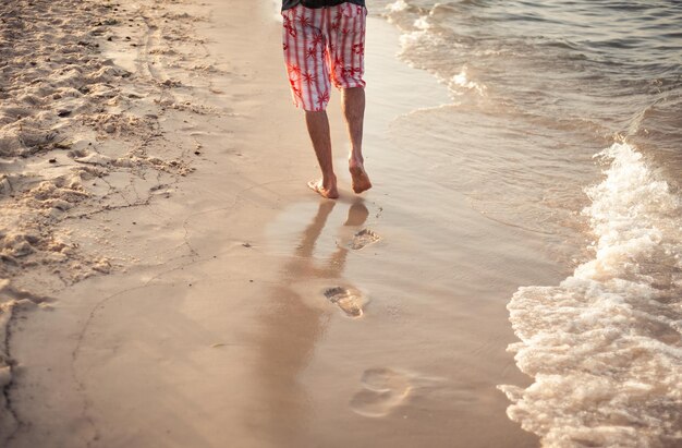 Un uomo cammina sulla sabbia in vacanza al tramonto