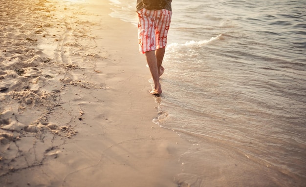 Un uomo cammina sulla sabbia in vacanza al tramonto