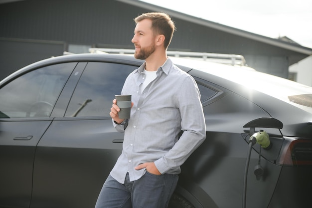 un uomo carica un'auto elettrica