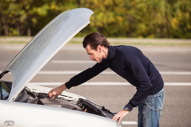 Un uomo cerca di riparare l'auto sulla strada