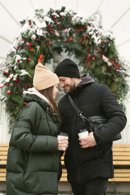 Un uomo che abbraccia la sua donna felice che beve tè o caffè caldo mentre cammina all'aria aperta