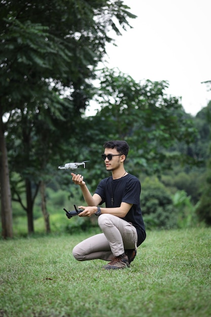 Un uomo che aziona il drone tramite telecomando nel parco verde Pilota di droni