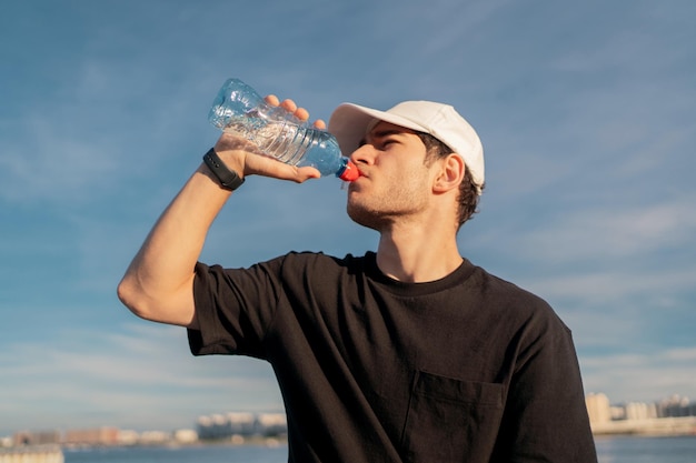 Un uomo che beve acqua pulita da una bottiglia durante una pausa tra gli allenamenti