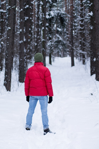 Un uomo che cammina in una foresta nevosa in inverno