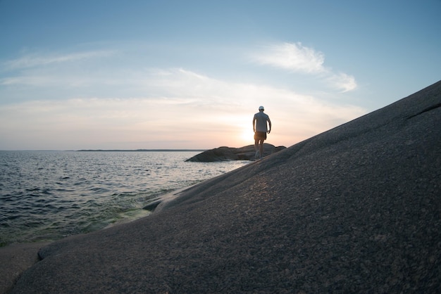 Un uomo che cammina lungo un mare roccioso Vista posteriore