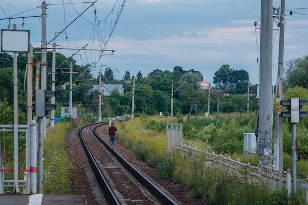 Un uomo che cammina sui binari ferroviari la sera.