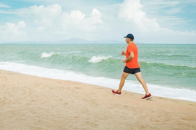 Un uomo che fa jogging sulla spiaggia di fronte all'oceano