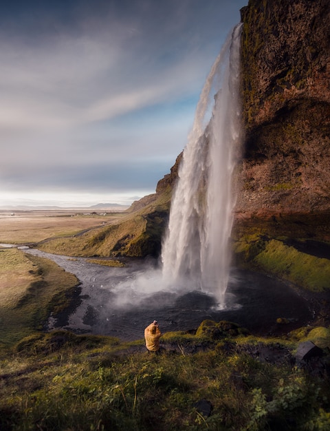 Un uomo che fotografa la cascata di Seljalandsfoss in Islanda