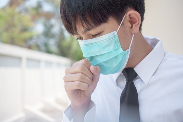 Un uomo che indossa una maschera chirurgica per coprirsi il naso Con tosse e starnuti A causa di malattie Al fine di prevenire la diffusione di virus e germi ad altri, i thailandesi asiatici usano la maschera facciale in caso di malattia