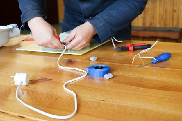 Un uomo che lavora un elettricista raccoglie il circuito elettrico di un grande lampione bianco