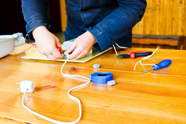 Un uomo che lavora un elettricista raccoglie il circuito elettrico di un grande lampione bianco