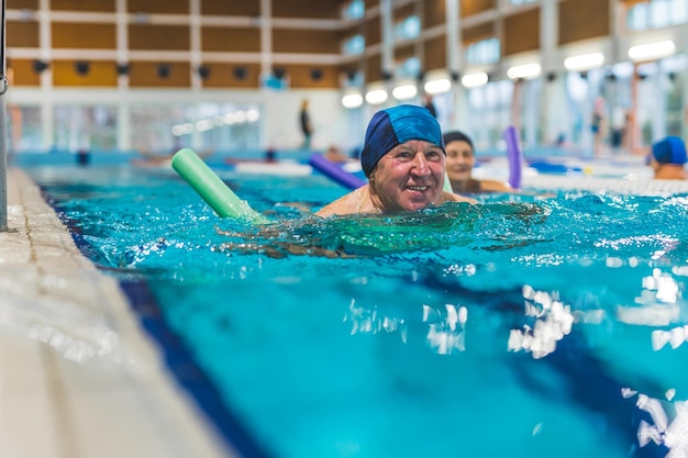 Un uomo che nuota in una piscina con un berretto blu in testa e un berretto blu in testa.