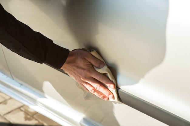 Un uomo che pulisce un'auto in un autolavaggio self-service, primo piano