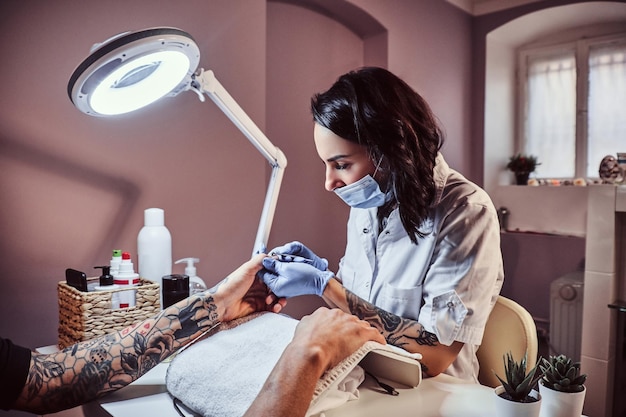 Un uomo che riceve una manicure nel salone di bellezza. Maestro estetista rifilare e rimuovere le cuticole.