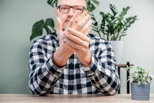 Un uomo che sente dolore alla mano artrite reumatoide e concetto di infiammazione delle articolazioni